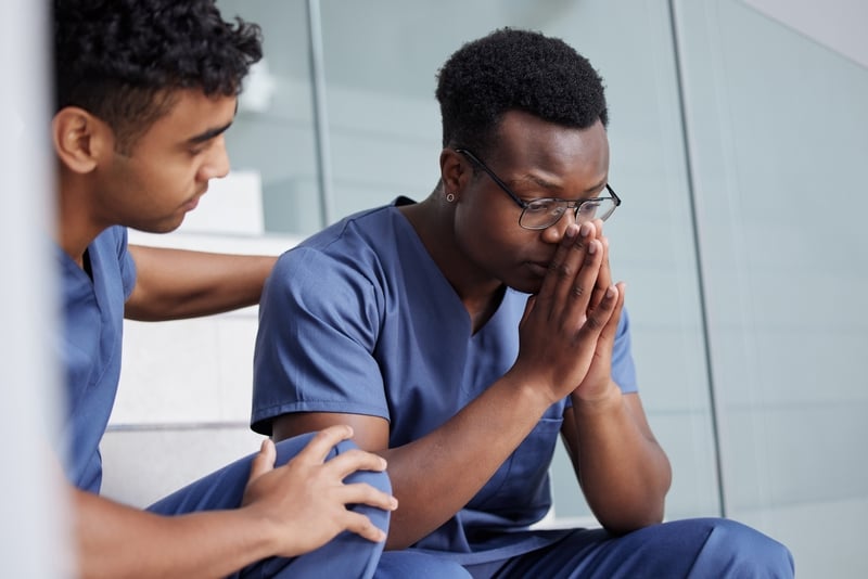 Photo d’un jeune médecin masculin consolant un collègue au travail